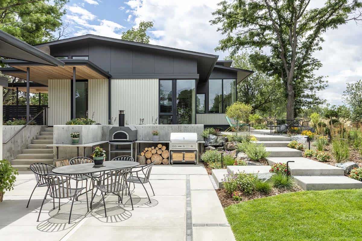 Backyard patio with outdoor kitchen, pizza oven, dining table, and tiered concrete garden steps