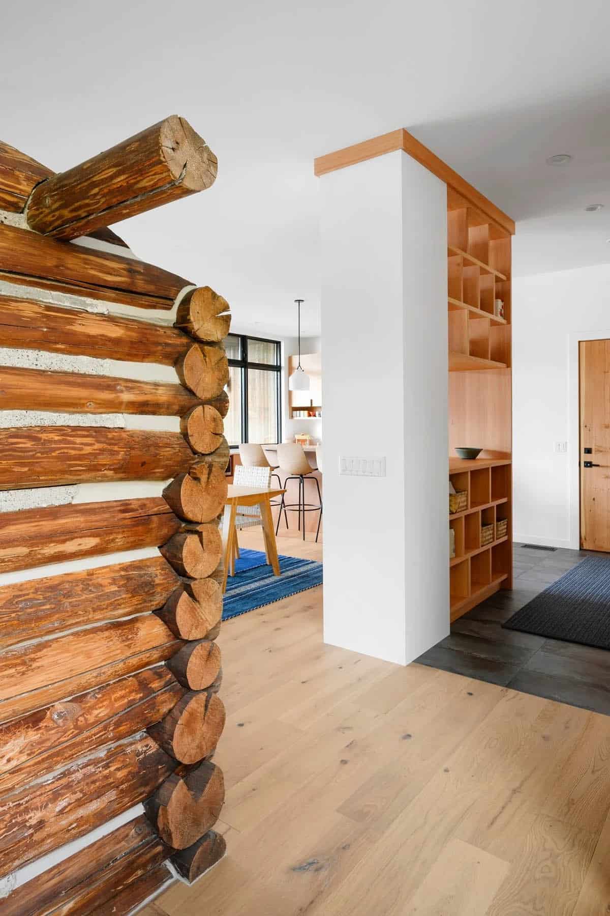 Interior hallway showing exposed log cabin corner joinery beside built-in wood shelving