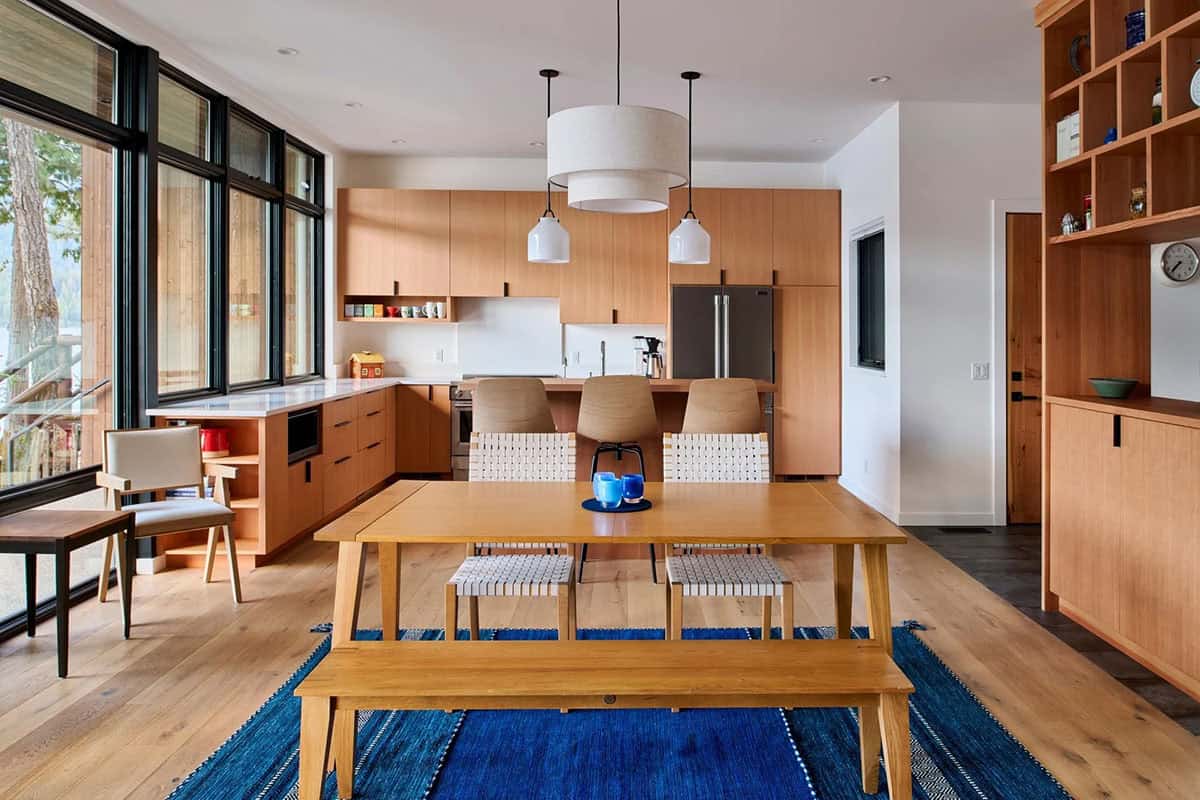 Kitchen with wood cabinetry, pendant lighting, and dining table with woven chairs