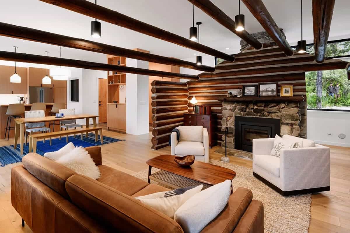Wide view of living room with log cabin core, stone fireplace, and leather sofa