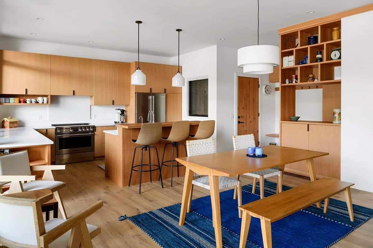 Kitchen and dining space with wood cabinetry, pendant lights, and blue striped rug