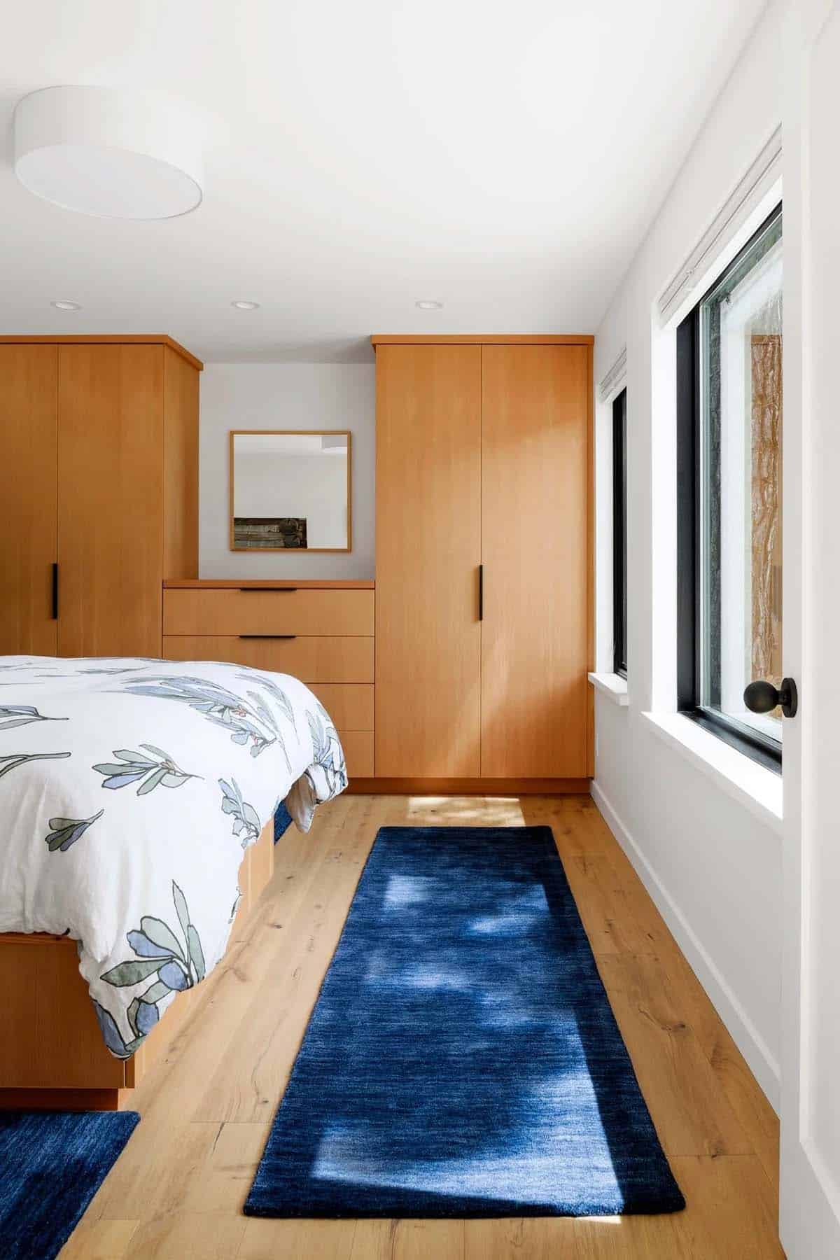 Bedroom with wood built-in wardrobes, floral bedding, and blue runner rug