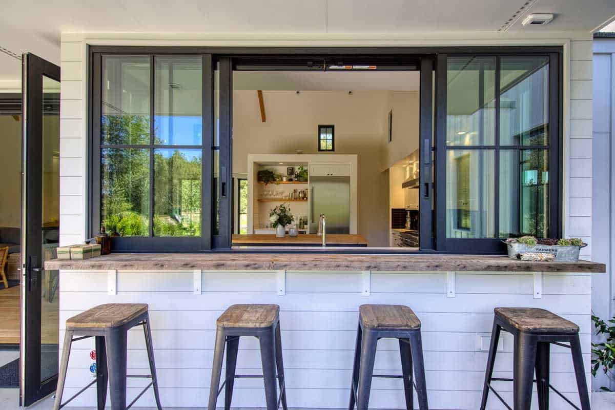 Close-up of the open sliding pass-through kitchen window with reclaimed wood bar and stools