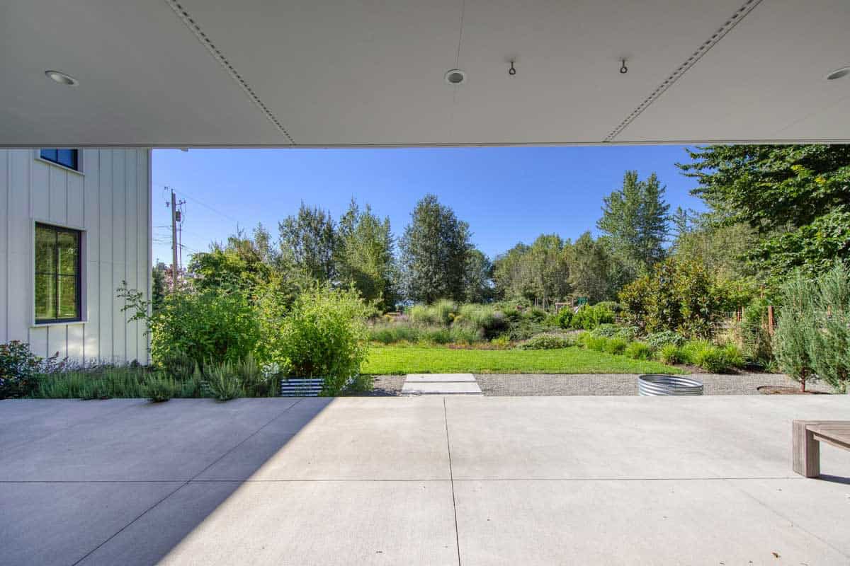 View from under the covered patio overhang looking out to a landscaped garden and lawn