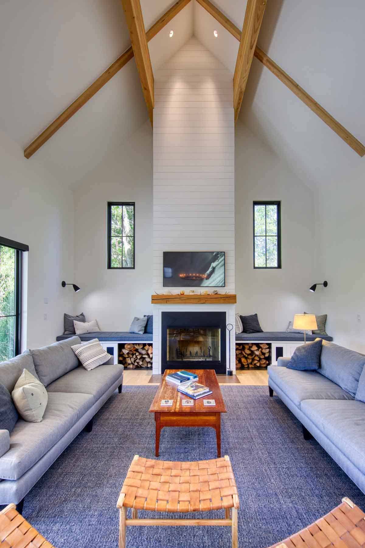 Vaulted living room with exposed wood roof trusses, tall shiplap fireplace, and built-in window seating