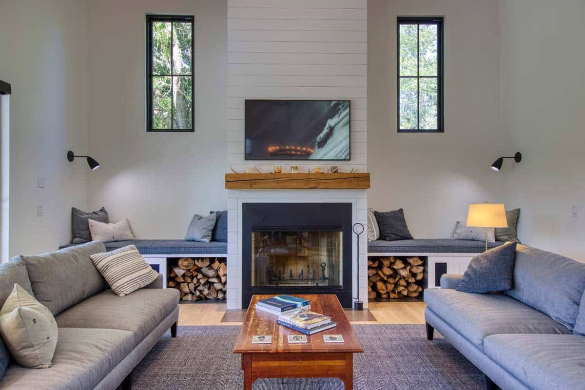 Living room fireplace flanked by built-in bench seating, blue sofas, and a wood coffee table