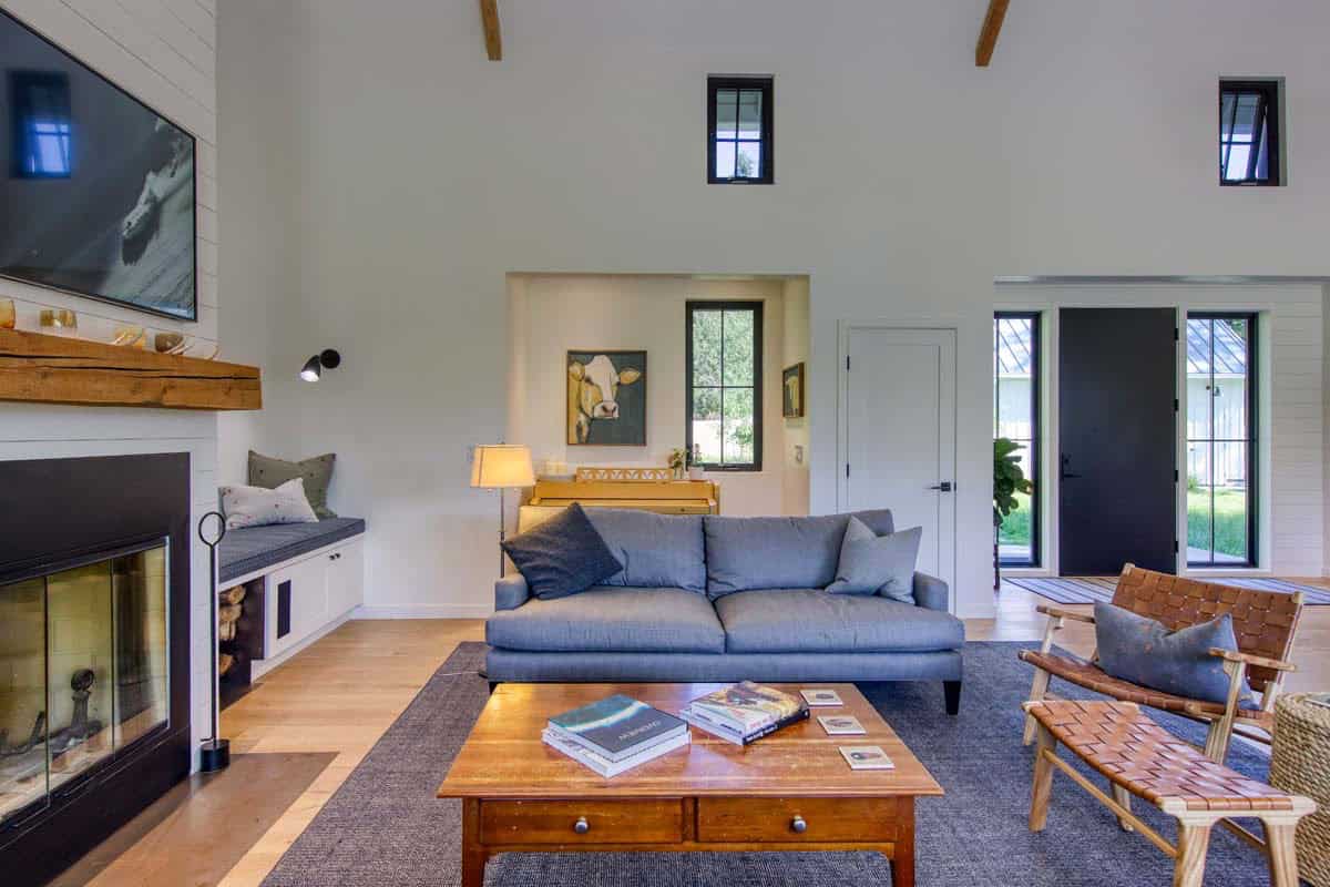 Living room with vaulted ceilings, exposed beams, blue sofa, fireplace, and window seating nook