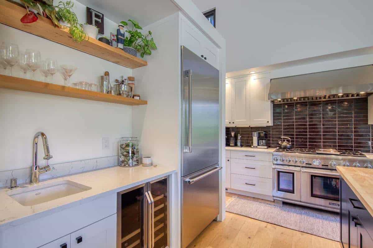 Kitchen wet bar with open wood shelving, wine fridge, and stainless refrigerator