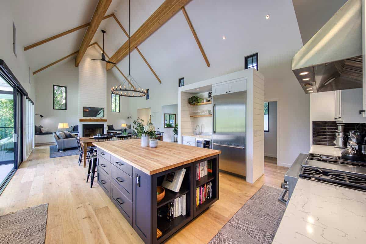 Vaulted great room with dark island, wood beams, and open sightline to kitchen and living area
