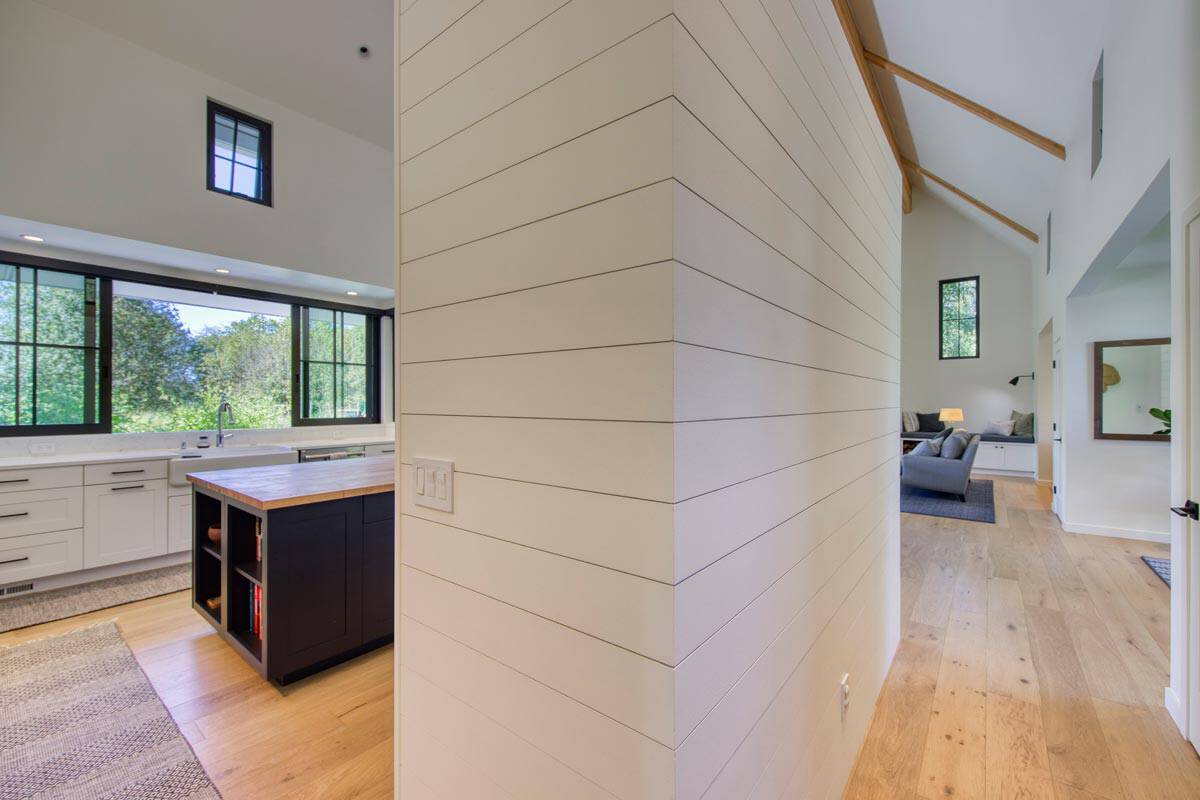 Interior hallway with shiplap accent wall connecting kitchen, dining, and living spaces