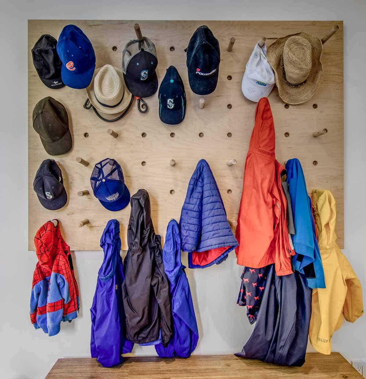 Pegboard mudroom organizer holding hats, jackets, and rain gear