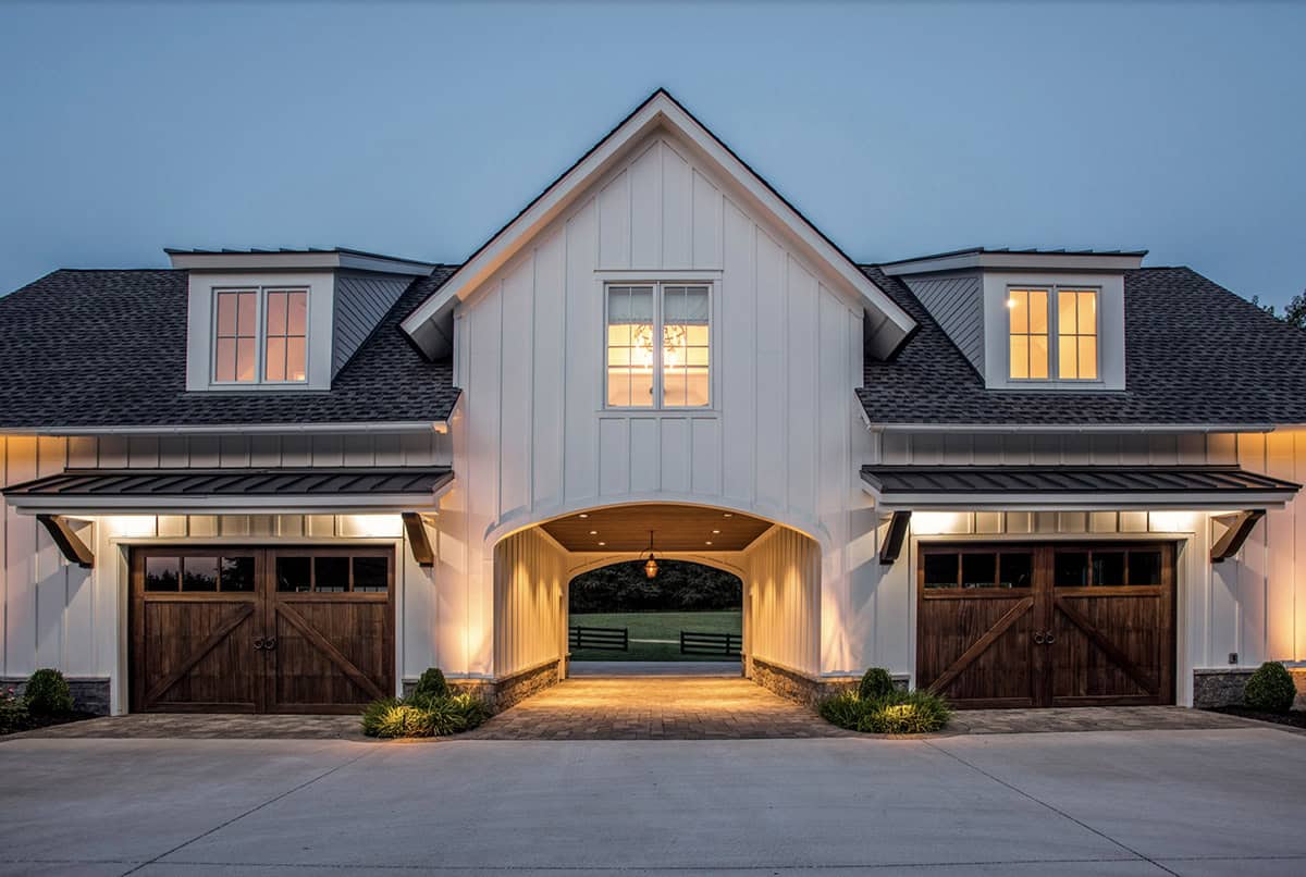 Evening view of the illuminated breezeway archway between garage bays