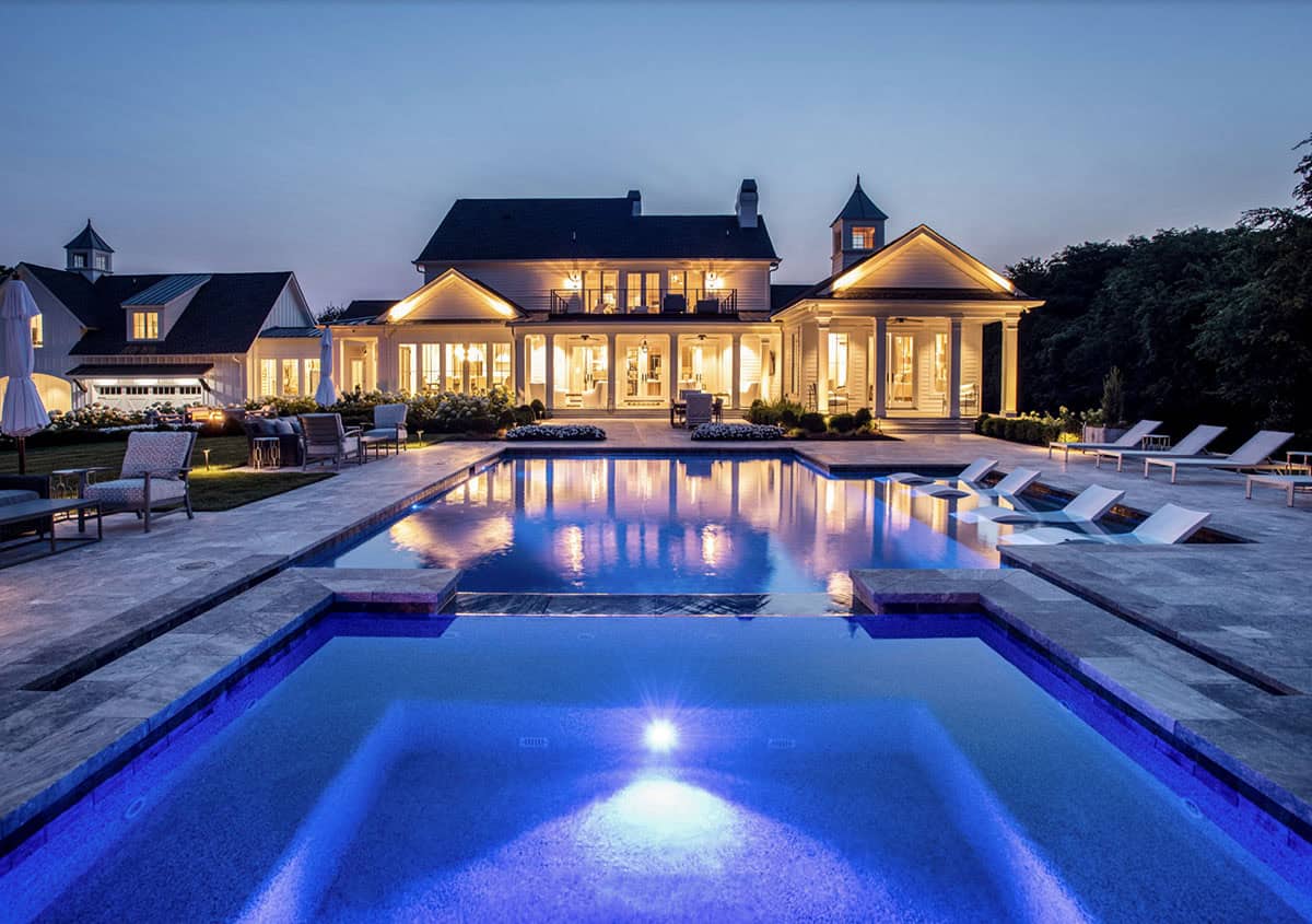 Evening view of the illuminated house reflected in the pool and spa lighting
