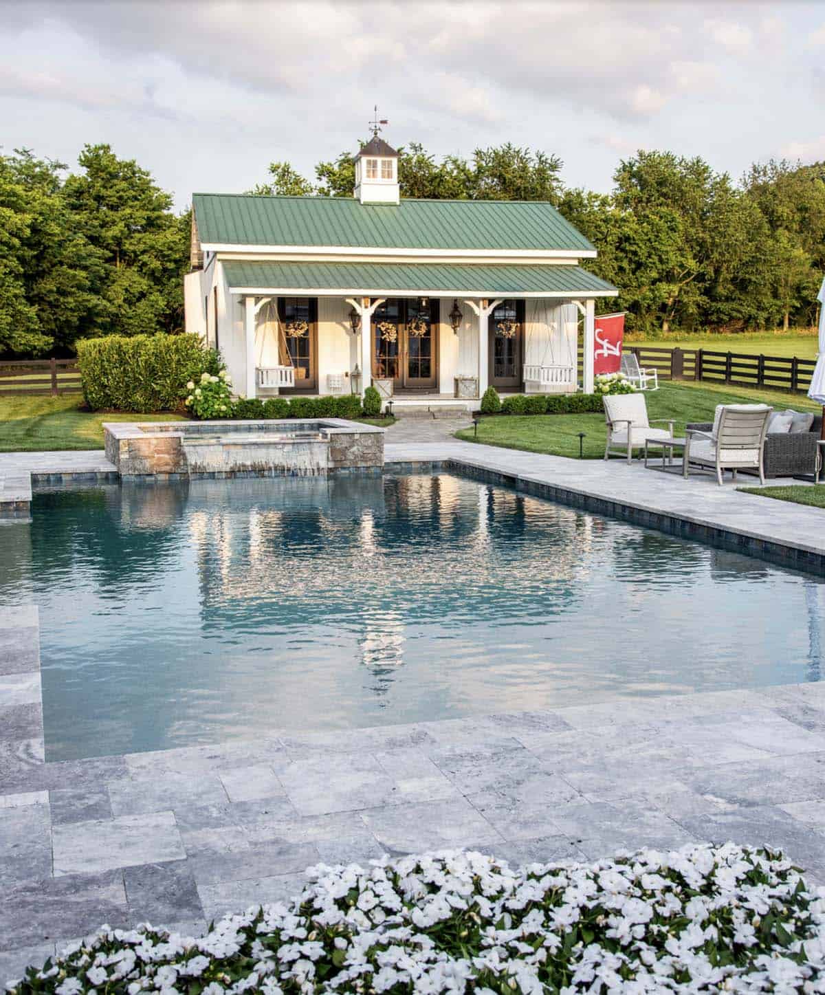 Green-roofed pool house viewed across the pool with spa water feature