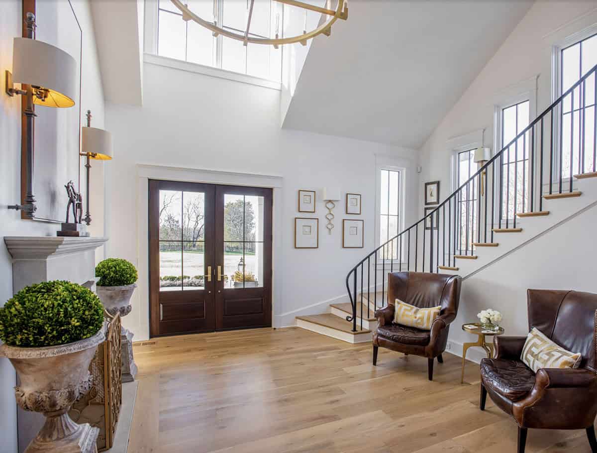 Two-story entry foyer with spiral staircase, leather chairs, and stone fireplace mantel