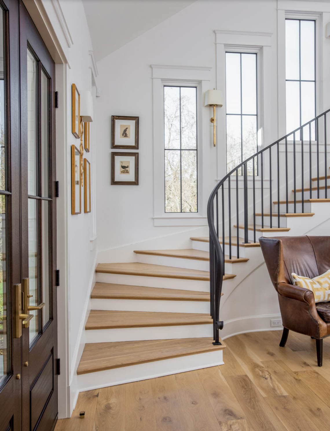 Curved wooden staircase with iron railing and gallery wall of framed prints