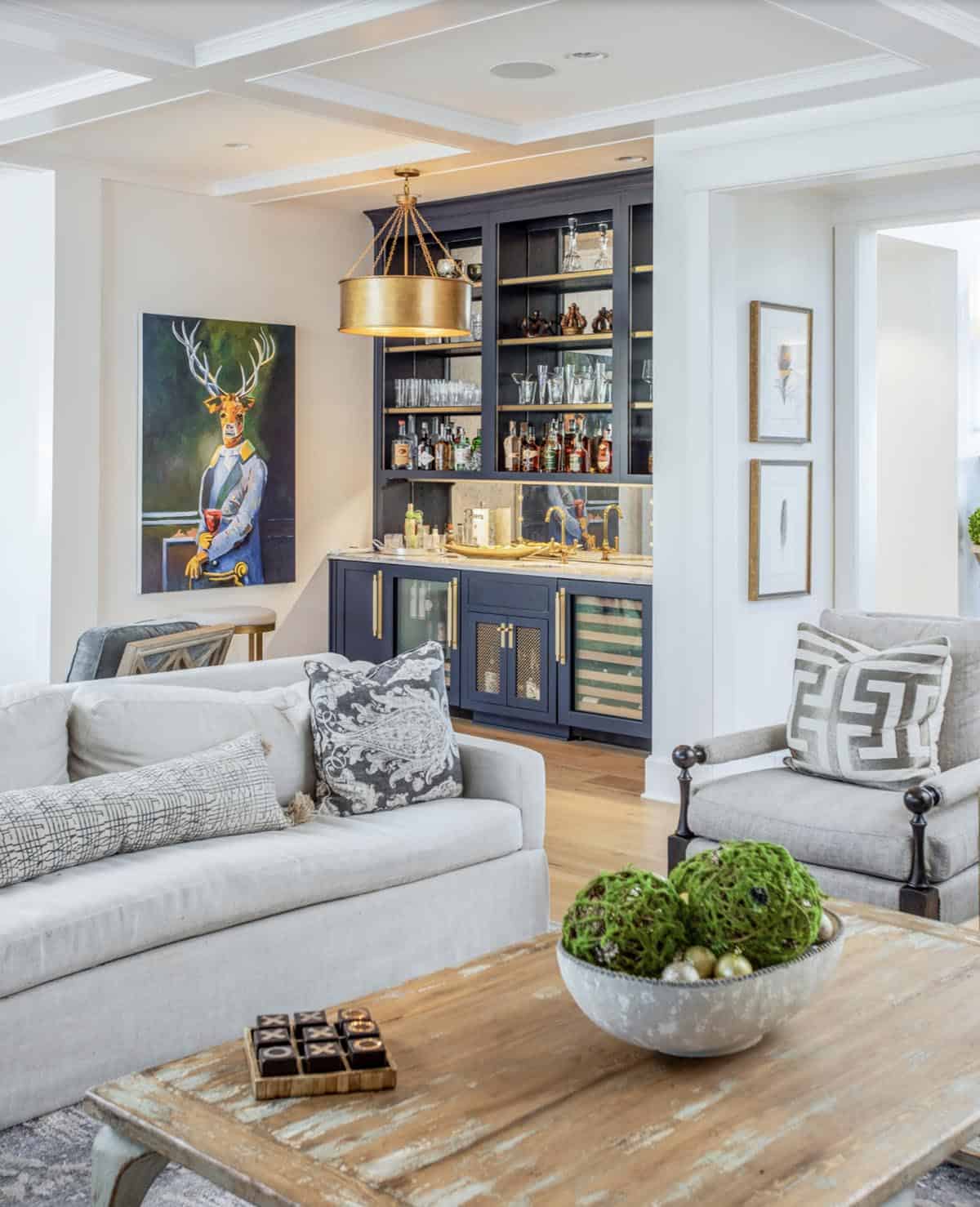 Living room with navy wet bar, whimsical deer portrait, and neutral seating