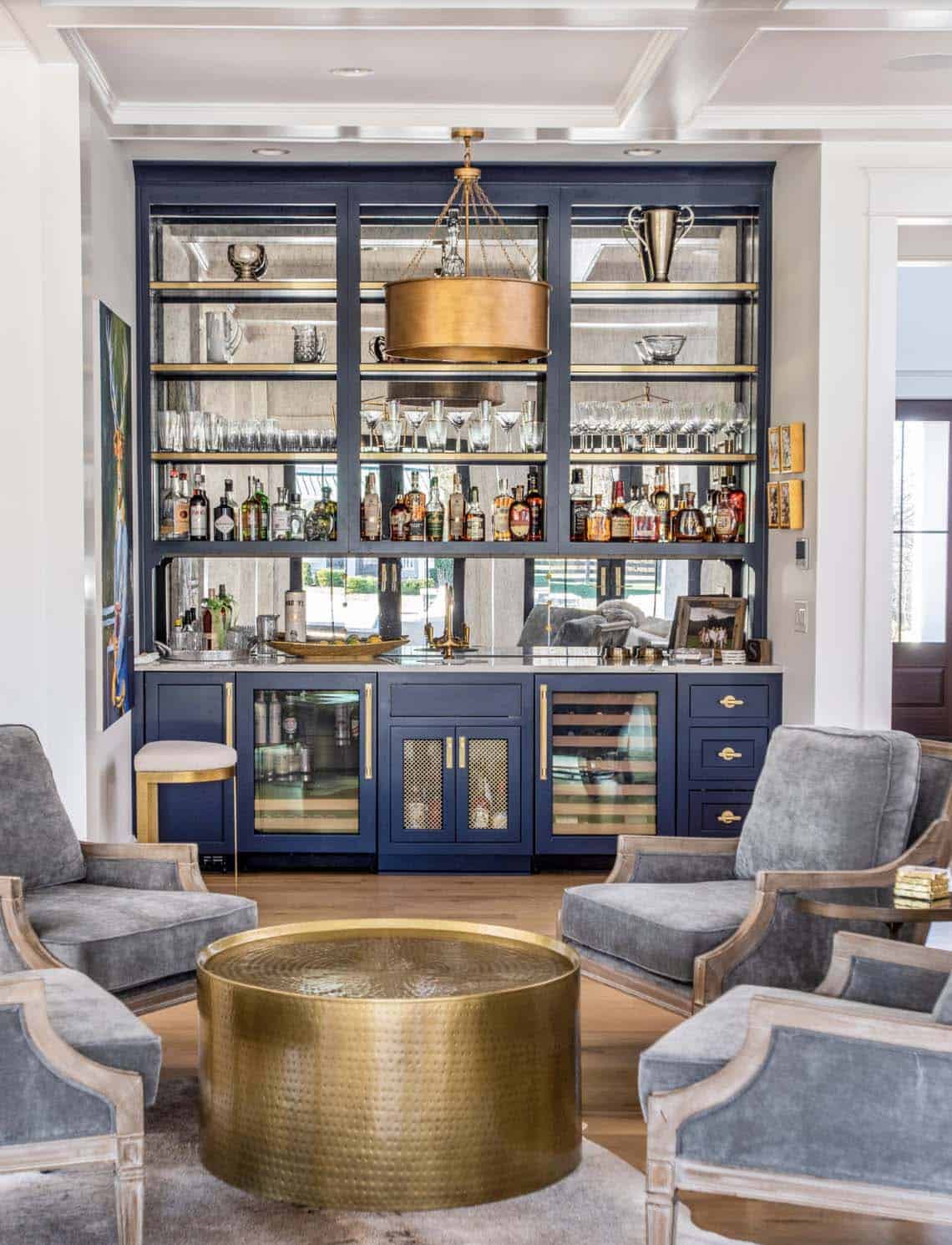Close-up of the navy built-in bar with mirrored shelves and brass pendant light