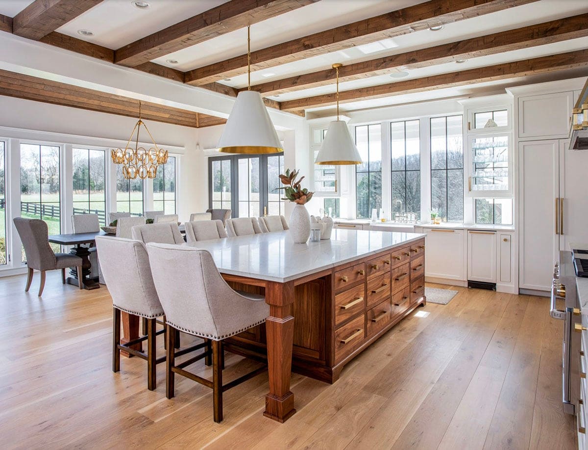 Open-concept kitchen with wood beam ceiling, walnut island, and white pendant lights
