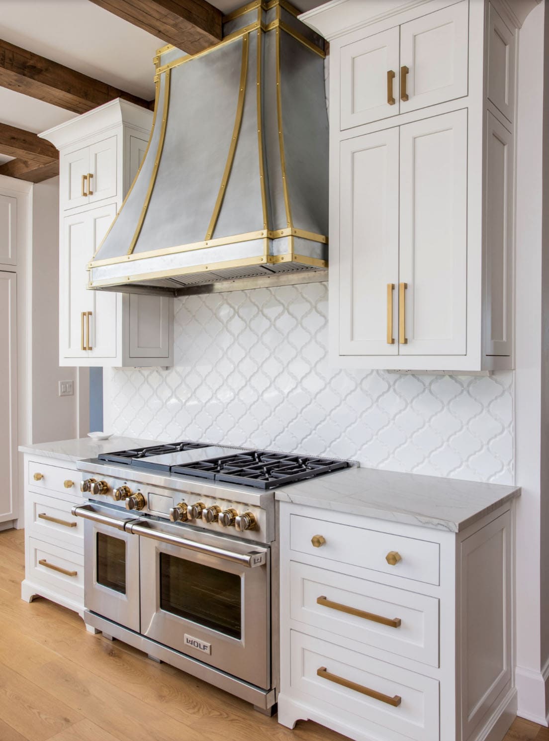 Close-up of the kitchen range with brass-trimmed hood and arabesque tile backsplash