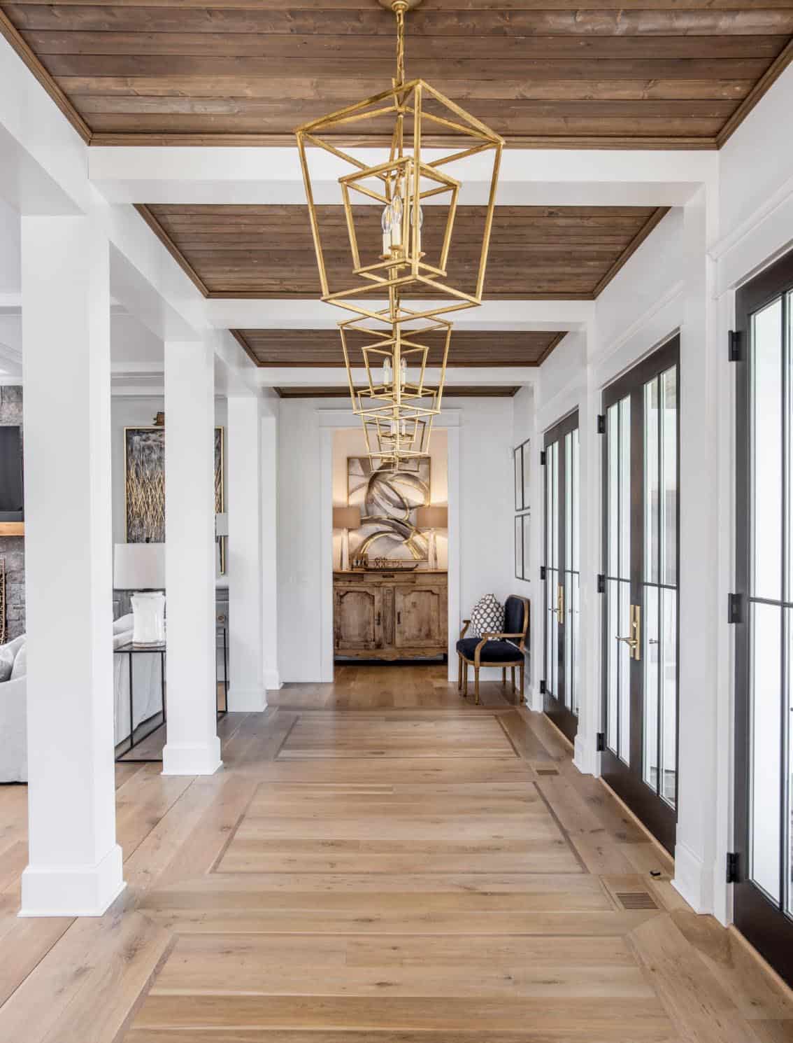 Hallway with wood-paneled ceiling, gold geometric pendant lights, and inlaid wood flooring
