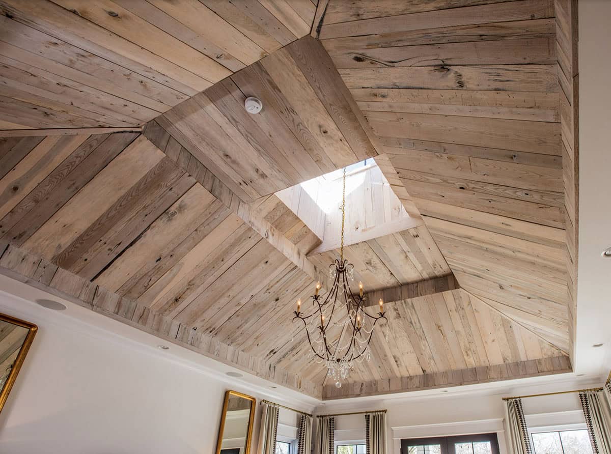 Close-up of the bedroom's reclaimed wood vaulted ceiling with skylight and chandelier