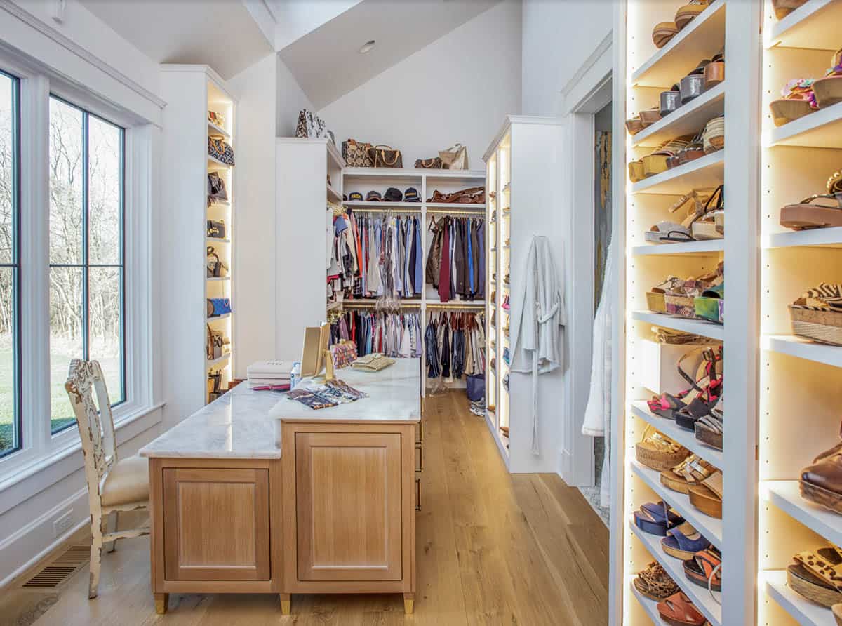 Walk-in closet with center island and illuminated shoe and handbag shelving