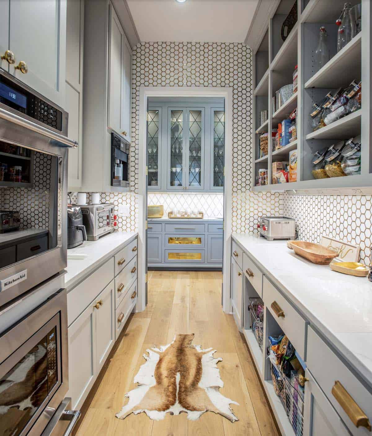 Butler's pantry with honeycomb tile backsplash, blue cabinetry, and animal-print rug