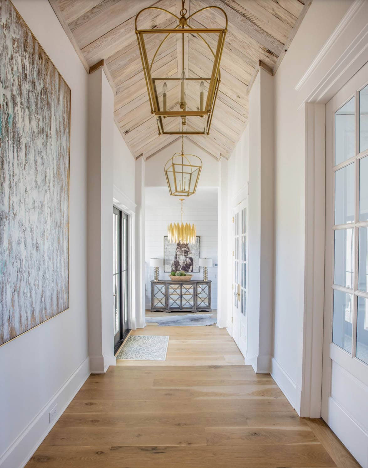 Hallway with whitewashed wood vaulted ceiling and brass lantern pendants
