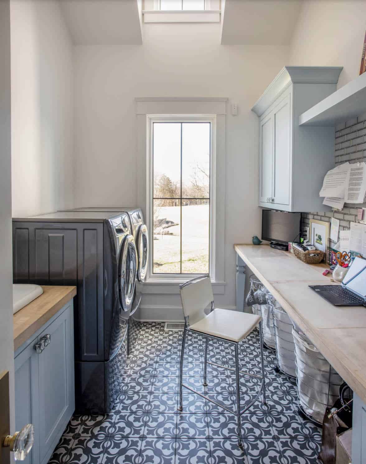 Laundry room with patterned tile floor, built-in desk, and front-load washer/dryer