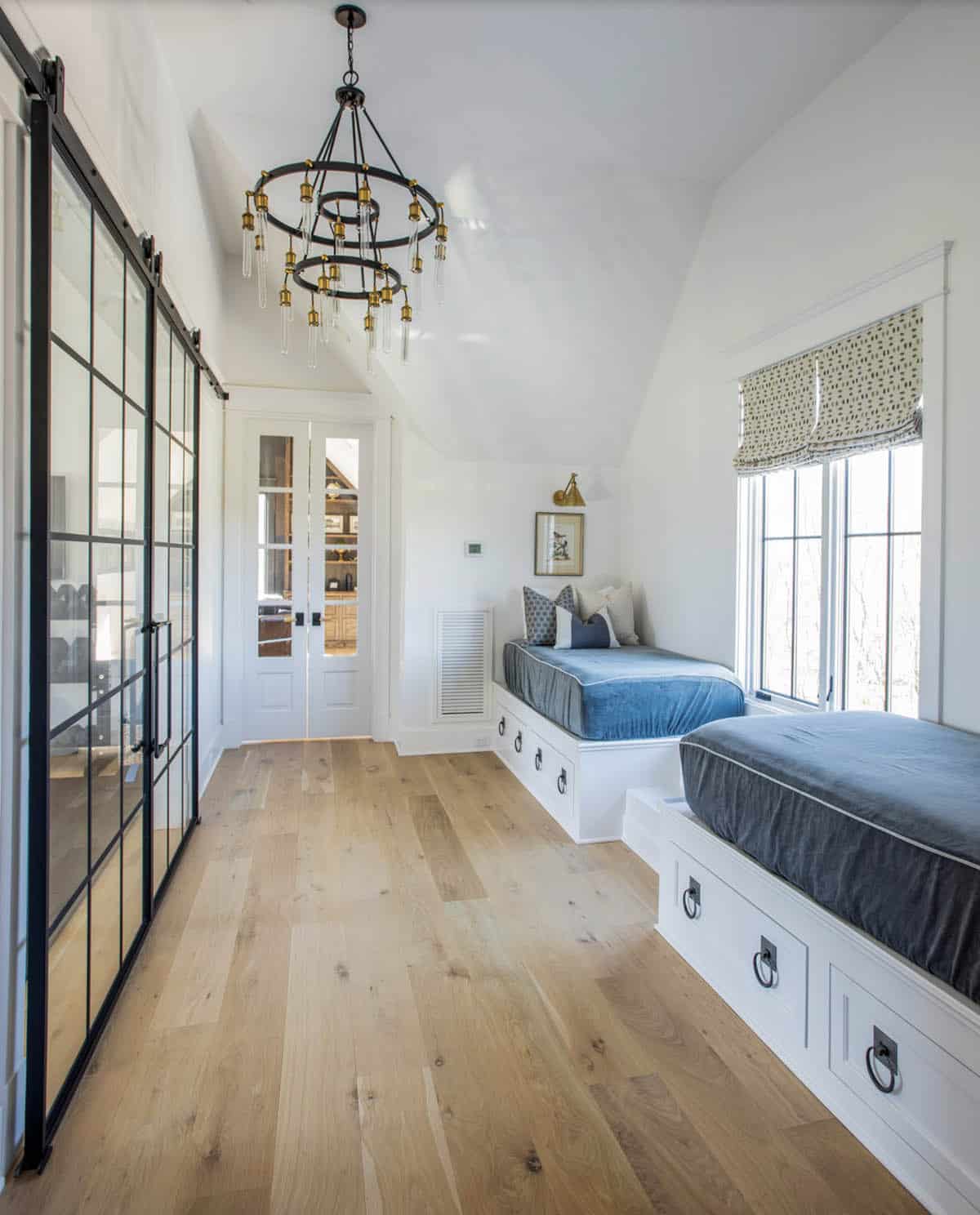 Bunk room with twin built-in beds, glass barn doors, and tiered chandelier