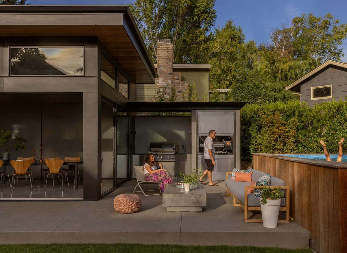 Couple on the patio near a built-in grill and hot tub, someone splashing in the water