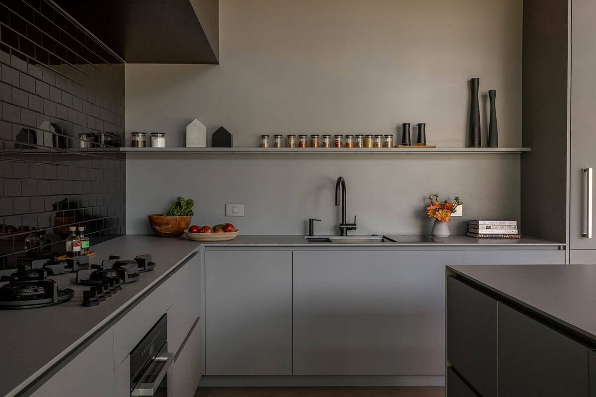 Kitchen counter with black subway tile, gray cabinets, black fixtures, and spice jars