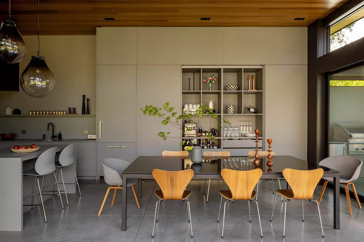 Dining area with a black glass table and Series 7 style chairs, open kitchen behind