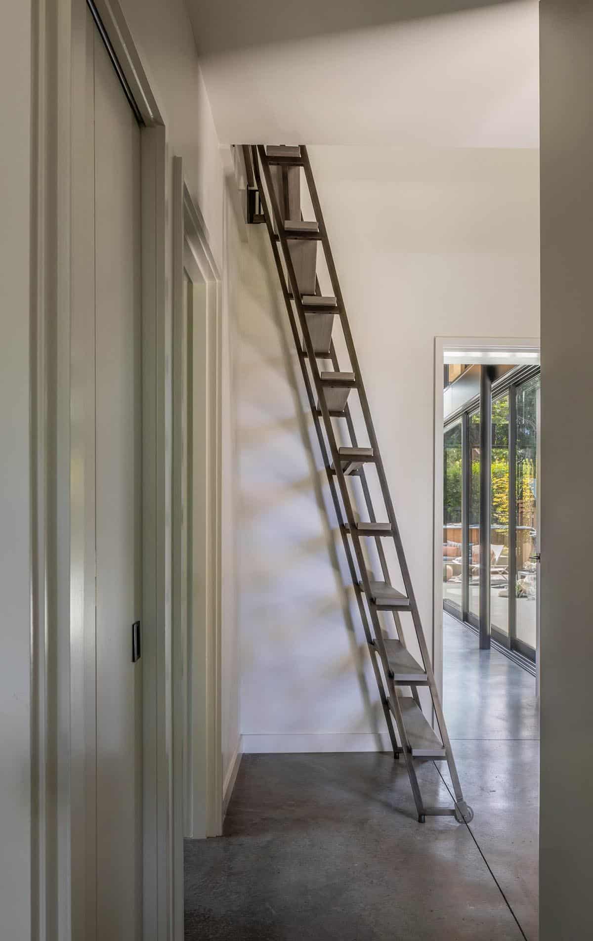 Foldable ladder to a loft space above a concrete-floored hallway