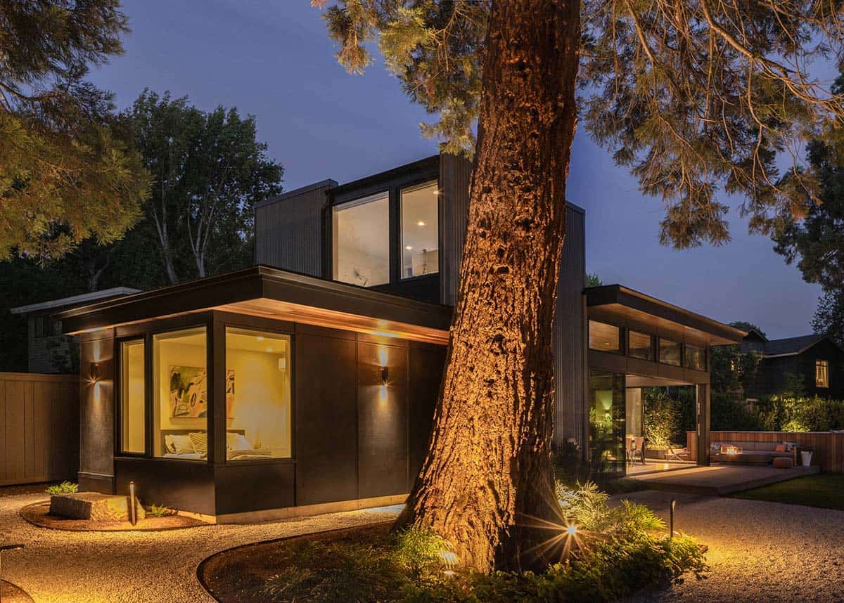 Twilight exterior of the Quincho glowing warmly beneath a mature sequoia and dusk sky