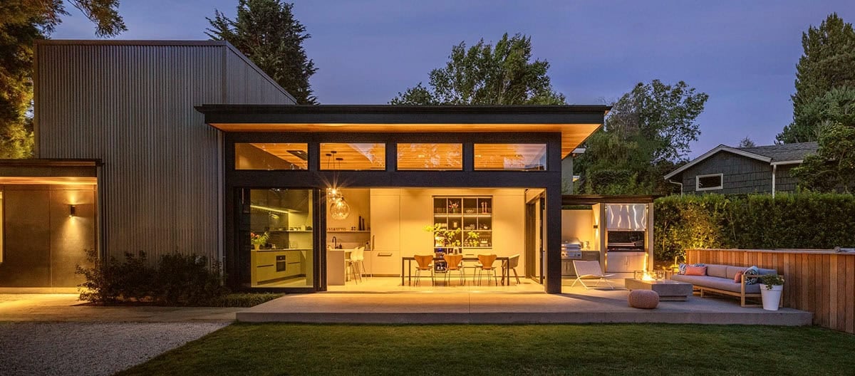 Evening view of the lit kitchen and dining pavilion opening onto the covered patio