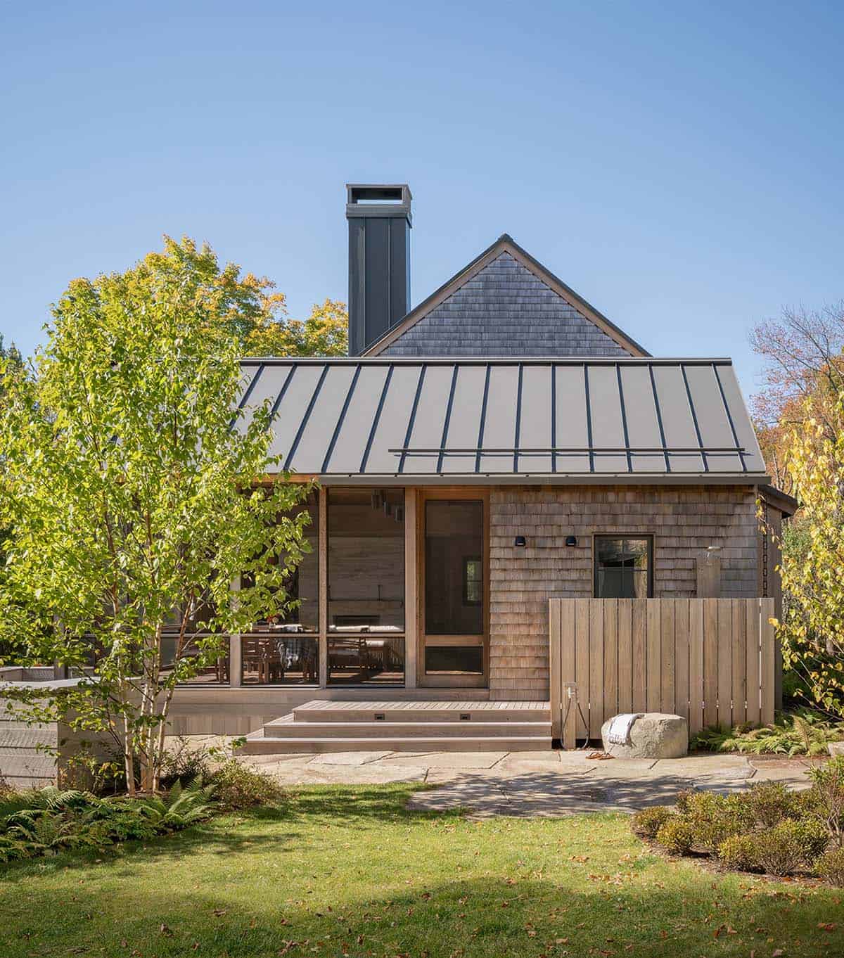 Cedar-shingled cottage with standing-seam metal roof, chimney, and screened porch