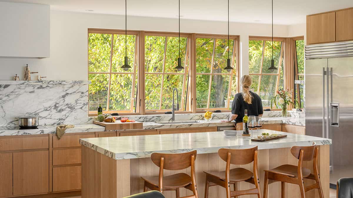 Kitchen with marble countertops, wood cabinetry, and angled windows overlooking greenery
