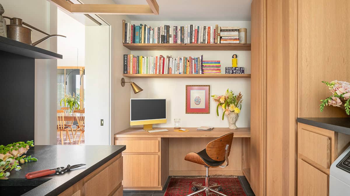 Compact home office nook with built-in desk, bookshelves, and a wood swivel chair
