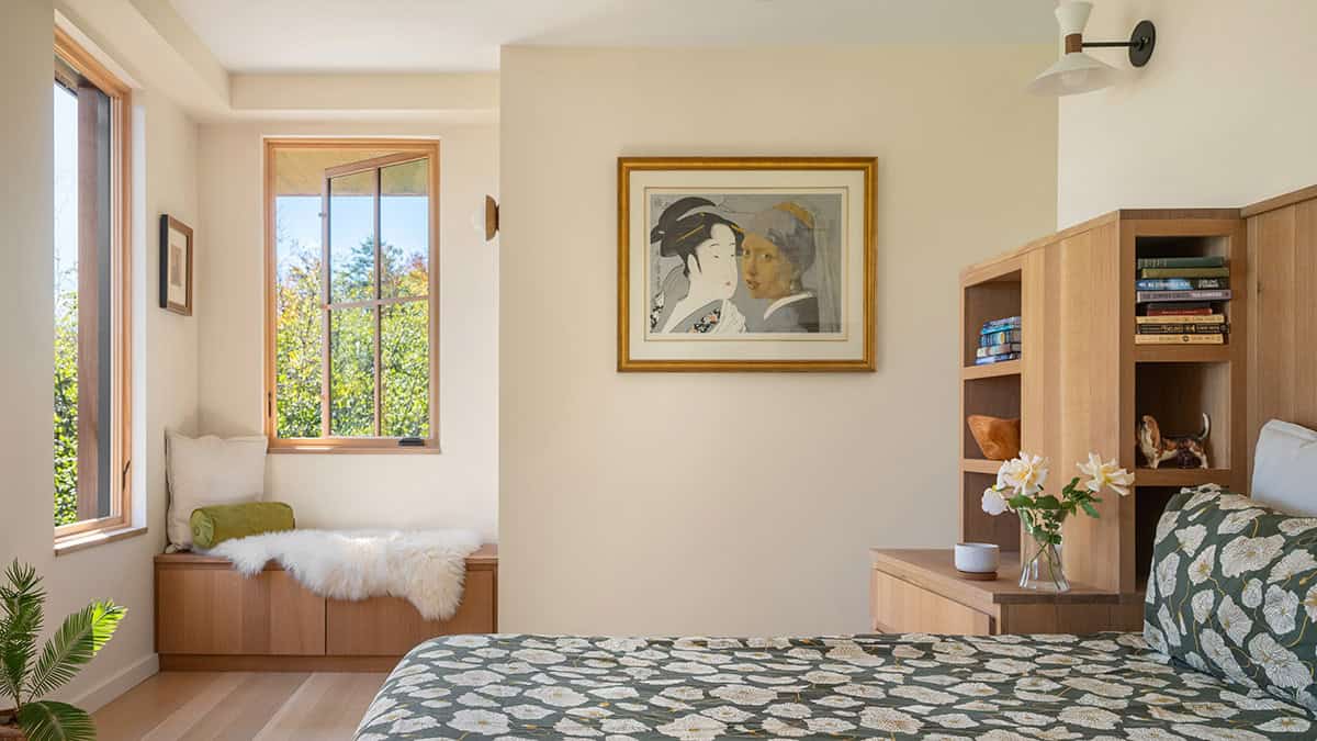 Bedroom corner with a window seat, framed artwork, and built-in wood shelving
