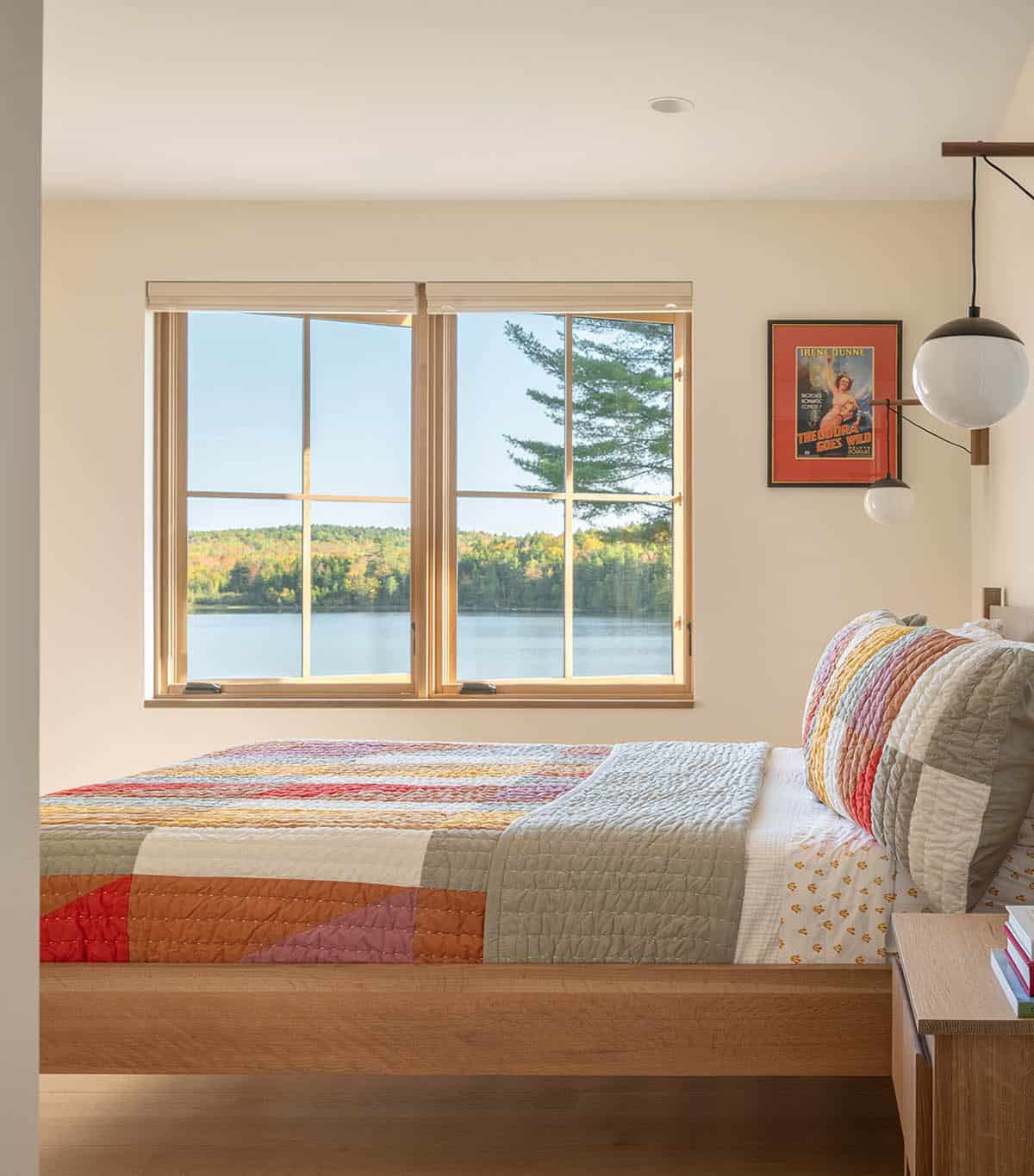 Bedroom with a patchwork quilt bed and a window overlooking a lake and fall foliage