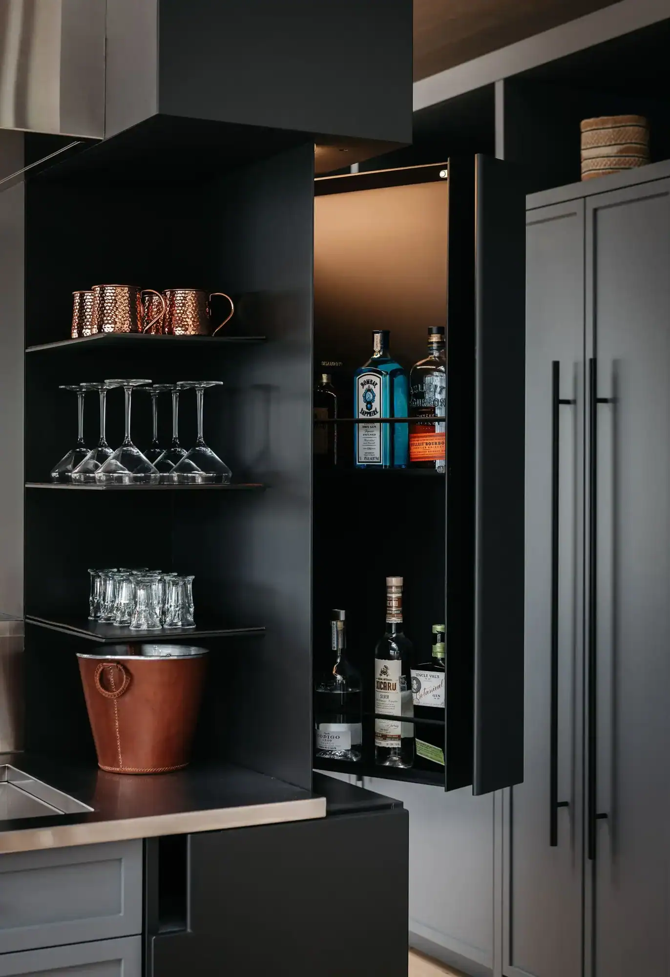 Open bar cabinet with glassware and spirits
