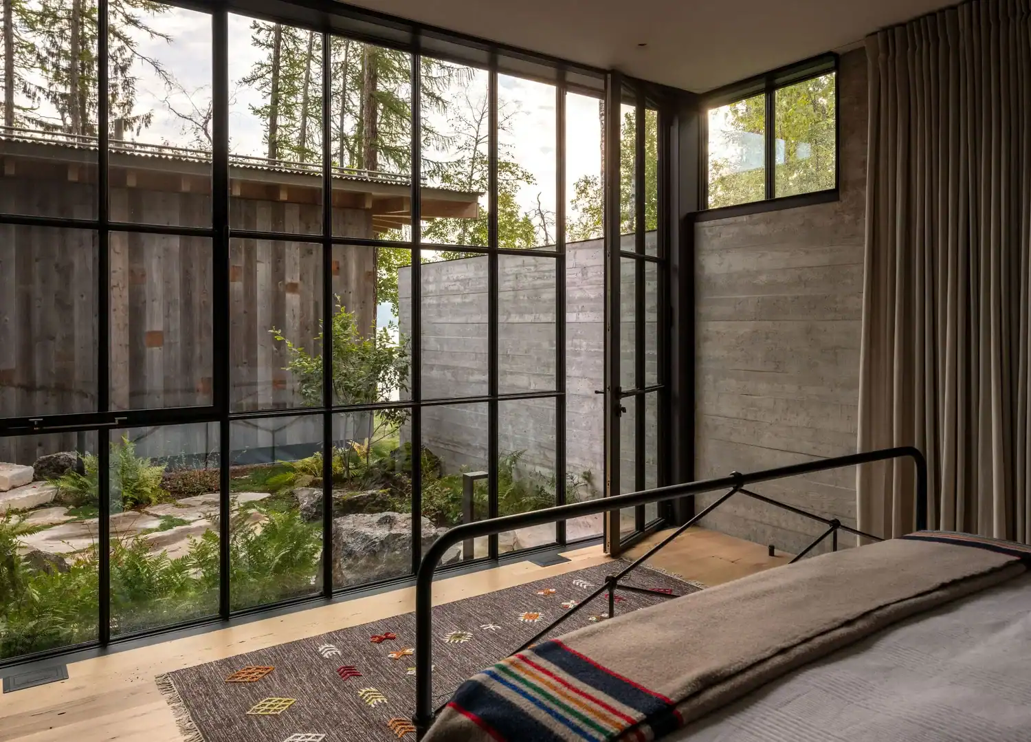 Bedroom corner with concrete walls and forest view