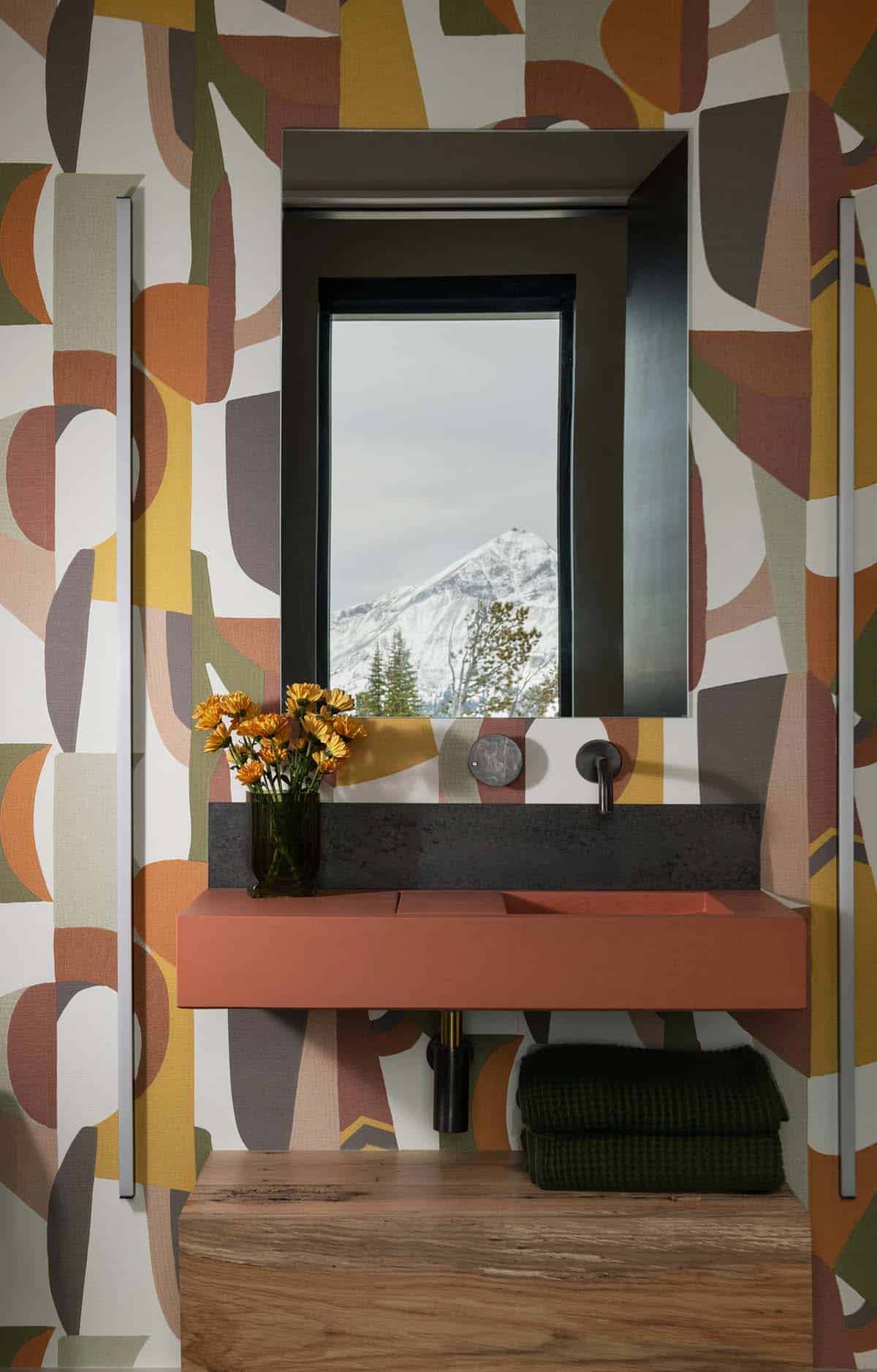 Powder room with bold geometric wallpaper, terracotta floating vanity, and mountain-view mirror window