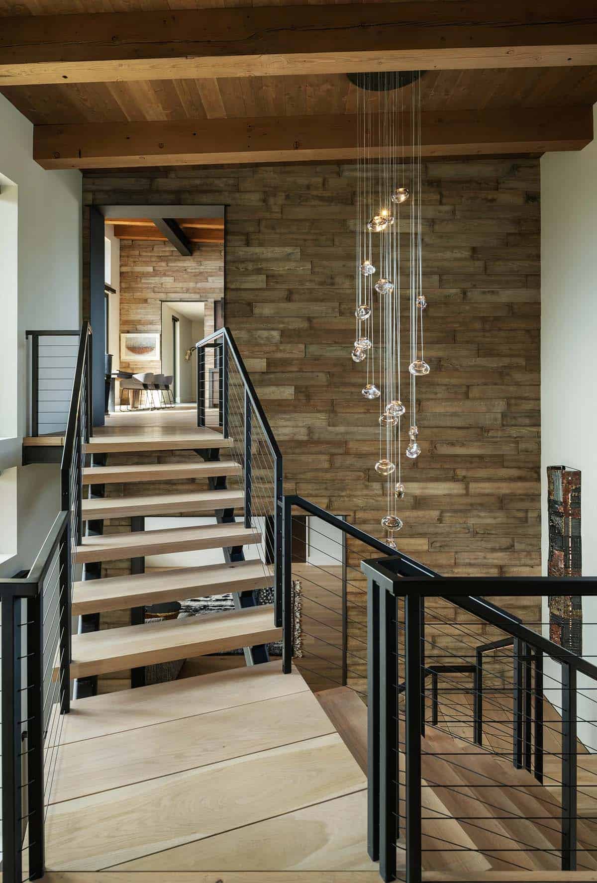 Open wood staircase with cable railings and a cascading glass bubble chandelier