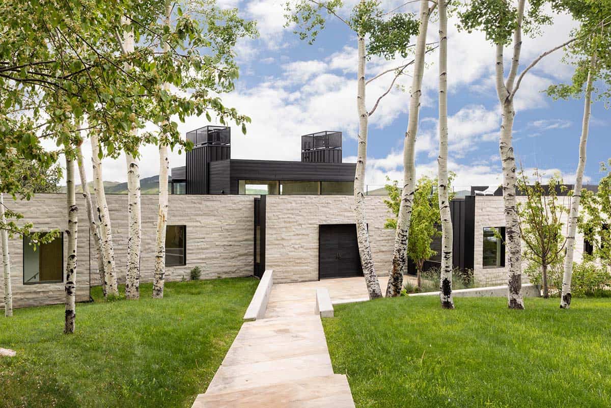Light stone house exterior framed by white-barked aspen trees along a stone path