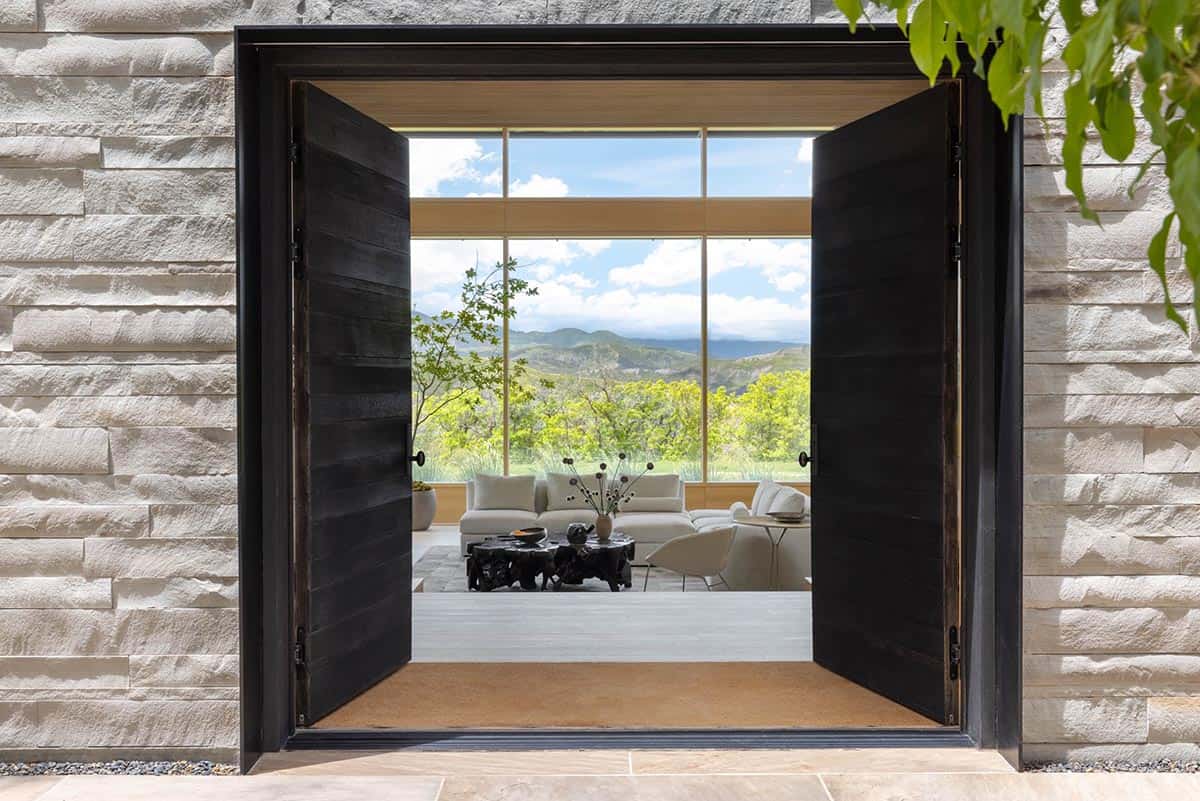 Open black double doors revealing a bright living room with mountain views