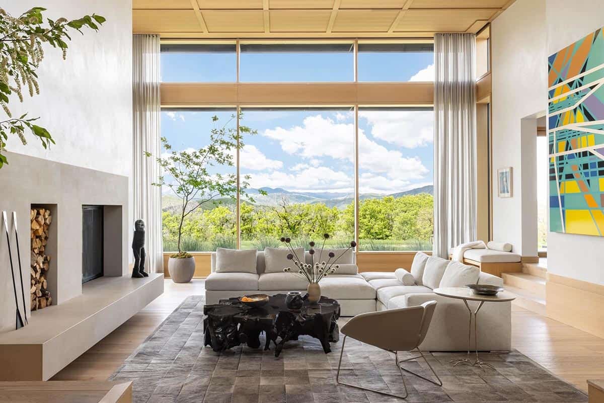 bright living room with white sectional sofa, wood ceiling, and floor-to-ceiling mountain-view windows