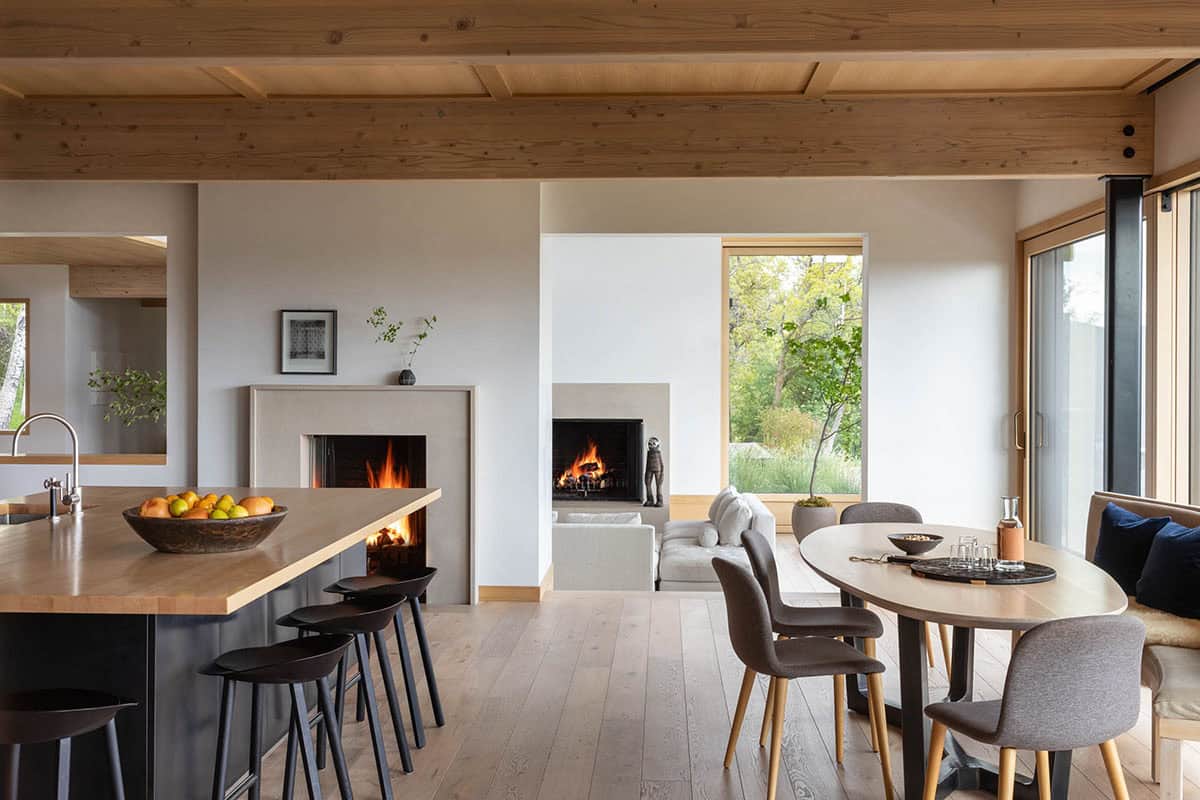 Open-plan kitchen and dining area with double fireplaces and wood beam ceiling